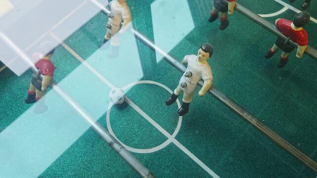 Static foosball players filmed from above, slow camera move and bright daylight