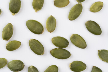 Green Pumpkin seeds closeup placed on a white background.