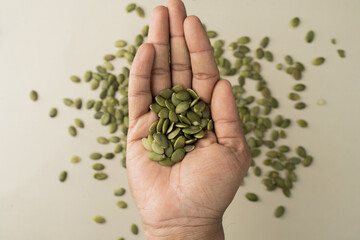 Green Pumpkin seeds are placed on a hand.