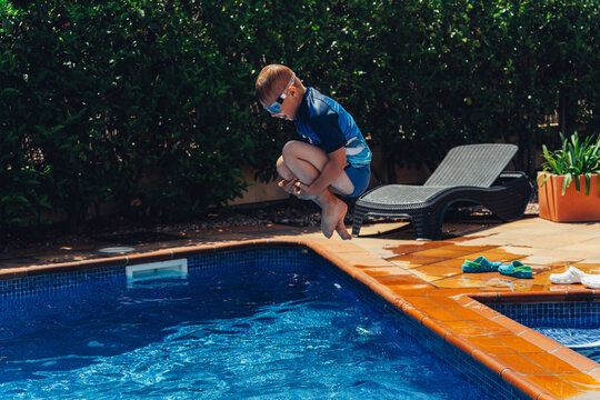 Boy jumps into pool with excitement during summer