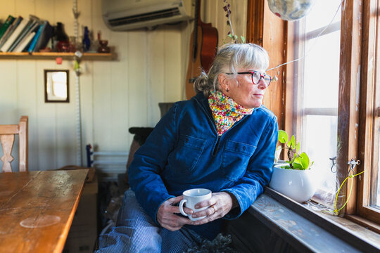 Relaxed Senior Woman with Coffee in Cozy Cottage Interior