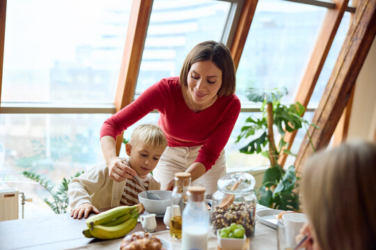 Mother helps her son with breakfast