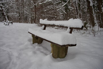A park bench covered in a thick layer of snow