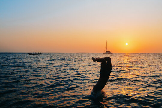 Silhouetted Man Diving into the Ocean at Sunset