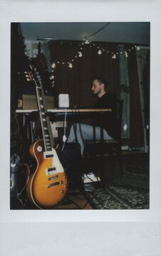 A male guitarist sits in a home music studio mixing a music track