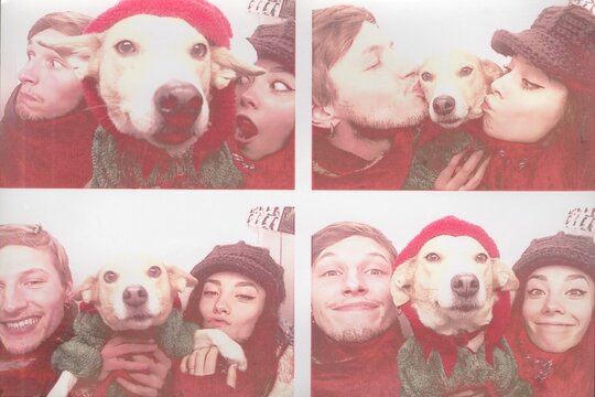 A couple takes a photo in a photo booth with their dog as a keepsake