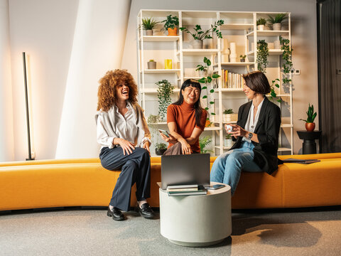 Three Friends Share a Casual Business Meeting on an Orange Couch