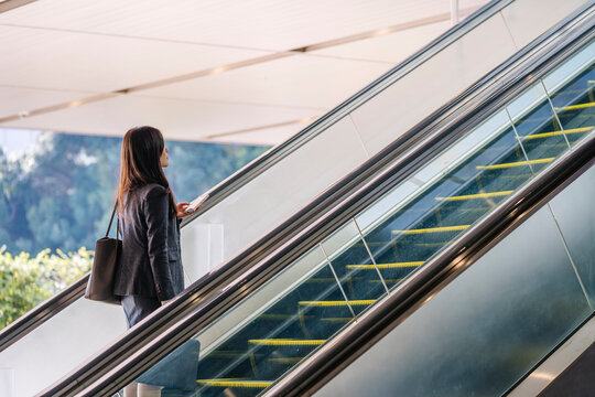 Japanese businesswoman riding escalator in modern city building