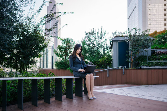 Japanese businesswoman working on laptop outdoors