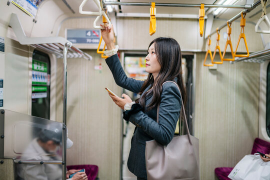 Woman commuting in train holding smartphone