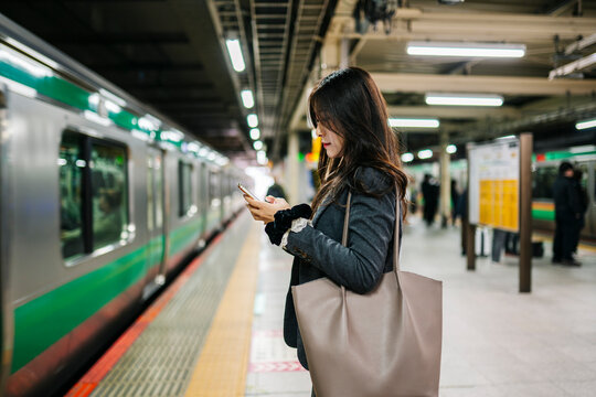 Japanese woman using smartphone at subway station in Tokyo