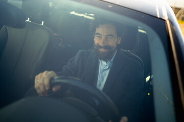 Man driving a car with a smile in a sunny outdoor setting