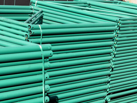 Stack of Green Metal Scaffolding Pipes at a Construction Site