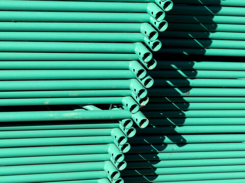 Stack of Green Metal Scaffolding Pipes at a Construction Site