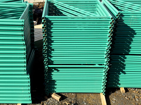 Stack of Green Metal Scaffolding Pipes at a Construction Site