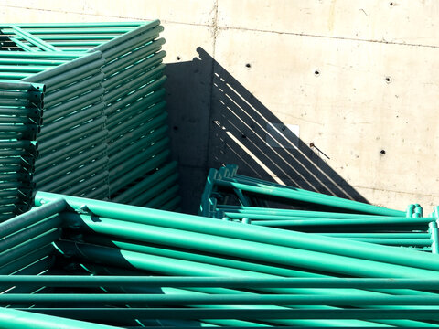 Stack of Green Metal Scaffolding Pipes at a Construction Site