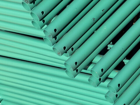 Stack of Green Metal Scaffolding Pipes at a Construction Site