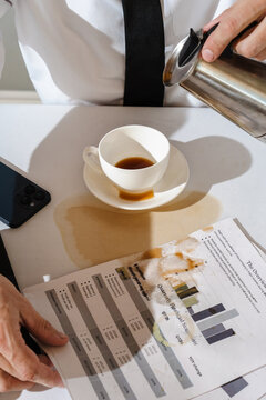 Spilled coffee soaking business documents on table