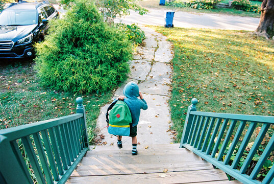 Child with backpack walks down stairs at home
