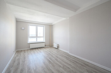 Obraz premium bright, empty room with light grey laminate flooring, off-white walls, large double window, white radiator, minimal fixtures, clean and airy atmosphere