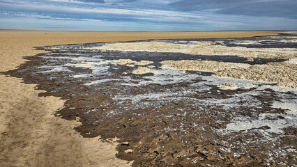 Lake Eyre dry salt flat with water coming in cloudy blue sky