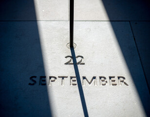 Sharp shadow from a vertical object on a smooth surface with a date marked on September 22