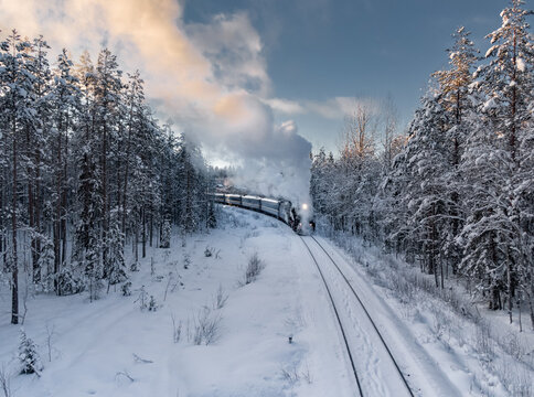 Historic Steam Train Travels Through Snowy Forest Landscape