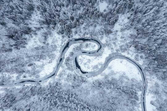 Winding River Through a Snowy Forest in Winter Landscape, aerial shot