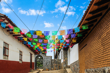 Traditional Mexican street decorated with colorful papel picado and adobe houses, cultural heritage, festive atmosphere and authentic rural town architecture in Mexico