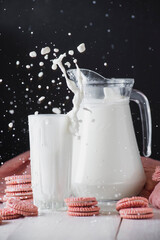 Milk splash rising from glass and jug on black background, high speed dairy photography © mykola