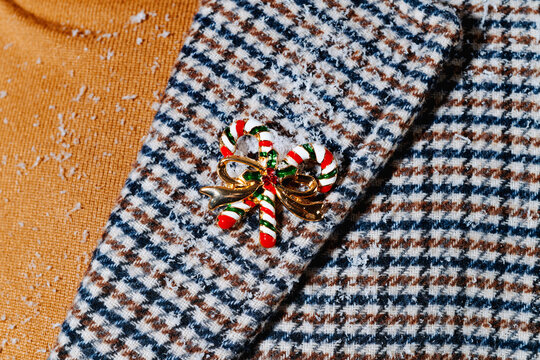 candy-cane brooch on the lap of a man covered with snowflakes