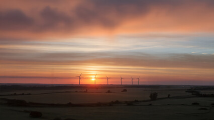 Wind turbines generating power at sunrise landscape.