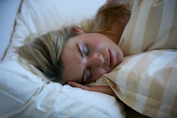 Woman, sleeping and rest in bed with peaceful morning for dreaming, fatigue and vacation at hotel....