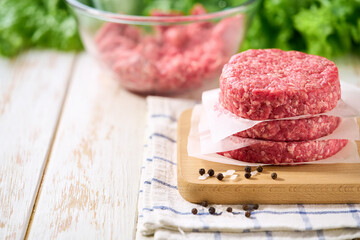 Stack of raw burger beef patties on a white table, selective focus. Natural meat product.