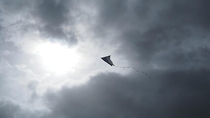 Fototapeta premium twinge. Broken kite string, kite drifting away in gray overcast sky, minimalist composition. wellbeing guides, coaching materials, designed for mental health education and mindfulness programs.