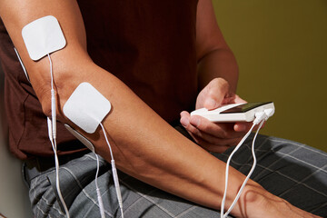 a man holding the control unit of an electrostimulation device