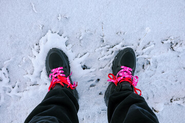 Sneakers with bright laces stand out against the snowy ground.