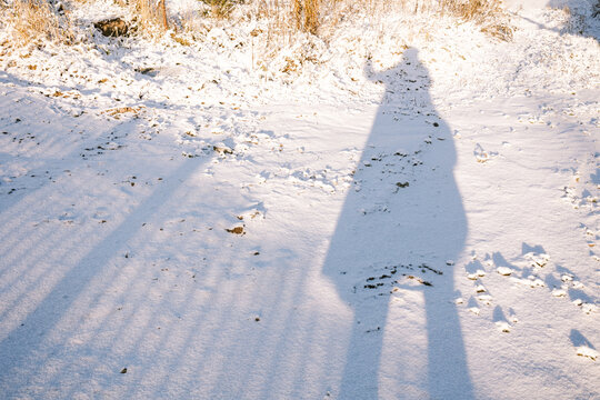 The shadow of a man in a winter landscape.