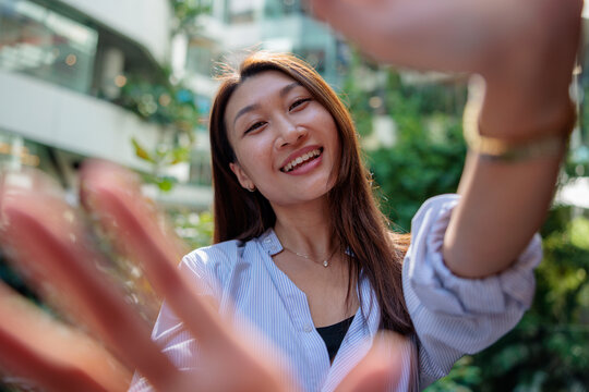 Smiling woman reaches for the camera in an outdoor setting.