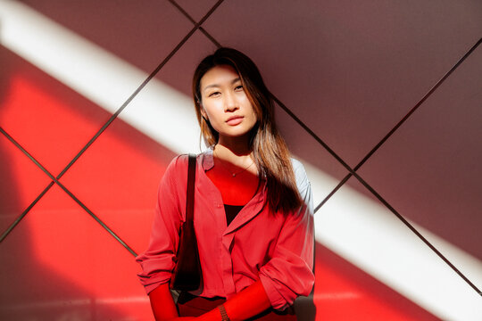 Woman in striped shirt stands in light and shadow.