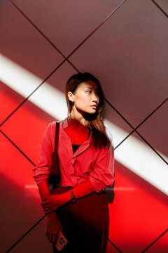 Woman in red light, looking away from the camera.