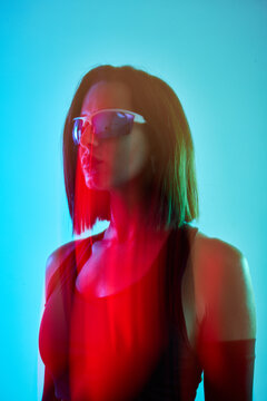 Stylish woman in sunglasses posing against a colorful background