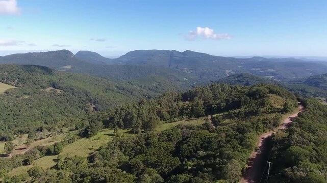 Cinematic drone aerial reveal shot rising and turning left over a rural dirt road on a ridge in Serra do Rabisco Rio Grande do Sul Brazil. High quality 4K Apple ProRes 422 10-bit nature footage.