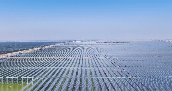 Aerial time-lapse of a large-scale solar photovoltaic power station under construction, fishery-solar complementary system on tidal flats. Clean energy and sustainable development in progress.