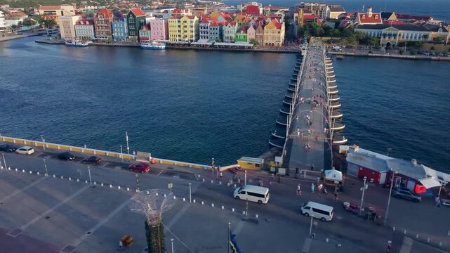 Tourists walking across floating bridge near bay in Curacao