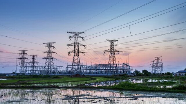 time-lapse of a large power substation in twilight glow, modern power infrastructure and grid connectivity with rural fields