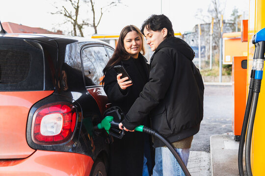 Lesbian Couple Hugging While Pumping Gas at a Service Station