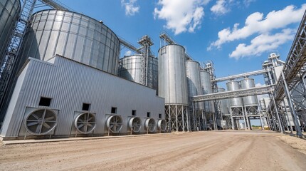 Low-angle perspective of an industrial agricultural complex with towering grain silos and processing facilities.