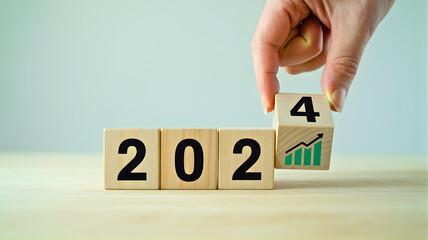 Conceptual image of a hand arranging wooden blocks to form the year 2024, symbolizing new beginnings, future aspirations, financial growth, and strategic business planning