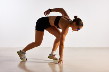 Runner preparing to sprint in athletic gear on a smooth floor